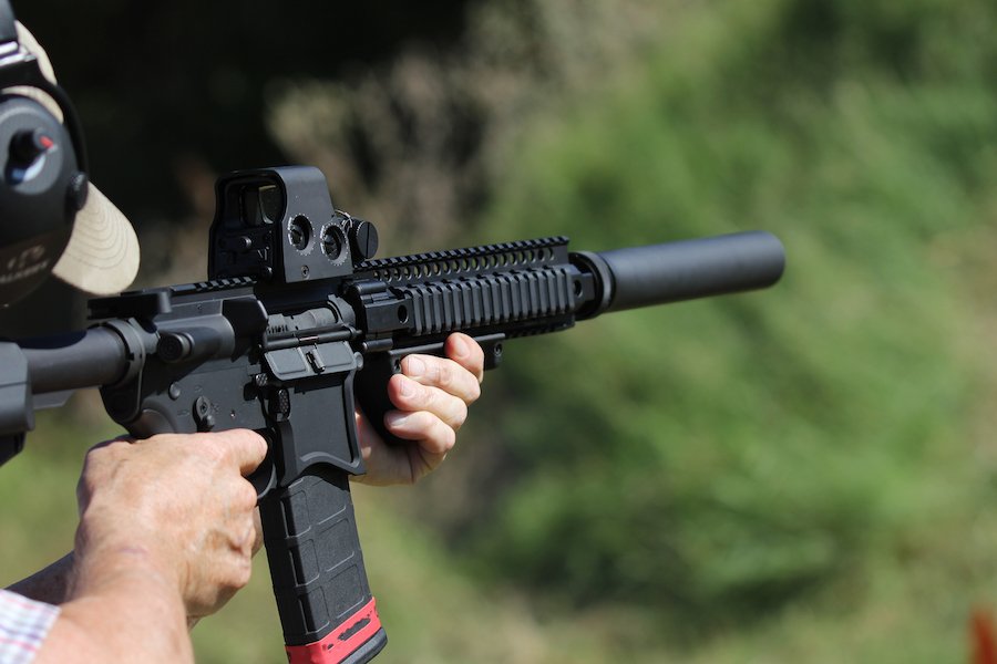 hombre sosteniendo un rifle con un dispositivo de bump stock