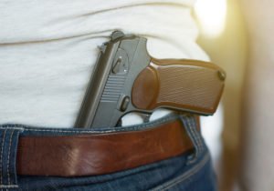 Man wearing gun half-tucked into his jeans, which is considered open carry