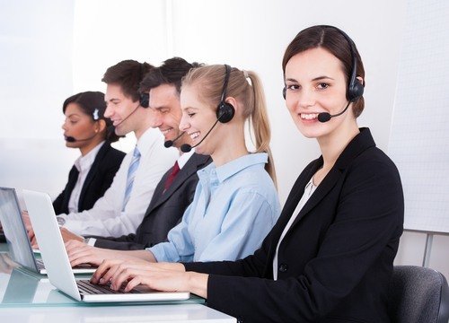 row of five receptionists with laptops and headsets