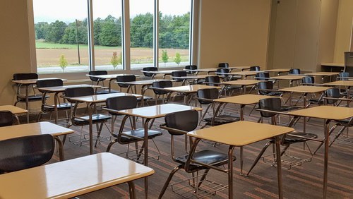 una clase sin estudiantes, solo con escritorios vacíos.
