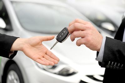 Close up of person handing car key to someone else