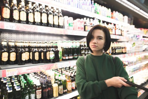 teenager at supermarket on the alcohol aisle - soliciting the sale of alcohol can be a crime in California