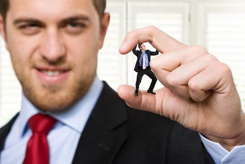 big man in suit squishing little man in suit in between his thumb and forefinger to illustrate unfair competition under California law