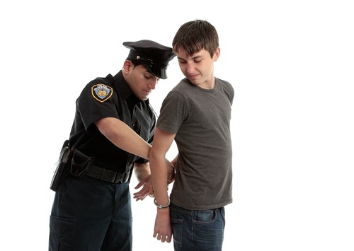 Police officer handcuffing a teenage boy
