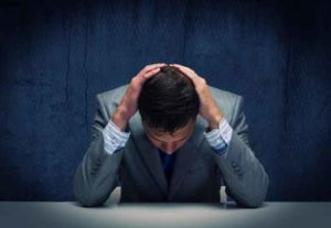 A man holding his head down in anguish over filing a guilty plea.