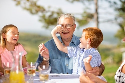 grandfather playing outdoors with his two young grandchildren