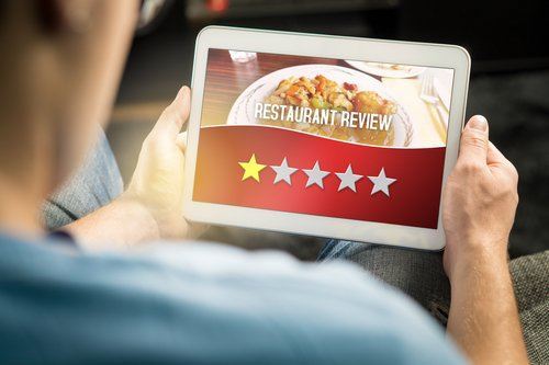 Man holding tablet about to leave a one-start review of a restaurant to illustrative business disparagement