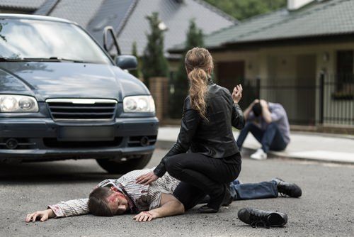 woman attending to an injured accident victim in the street