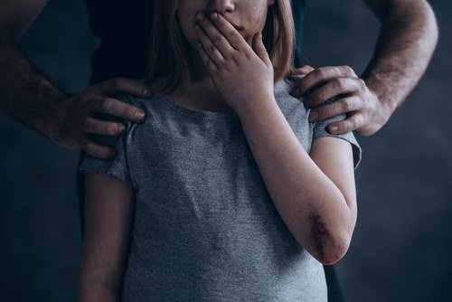 hombre colocando sus manos sobre los hombros de una niña joven