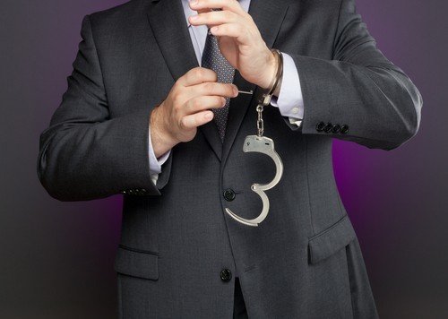 Man in suit with unclosed handcuffs