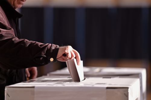 Hand putting ballot into ballot box