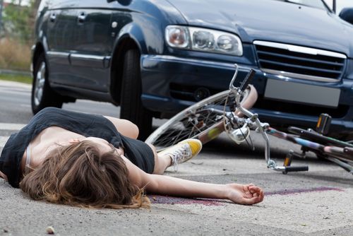 woman on ground after crash between car and bike