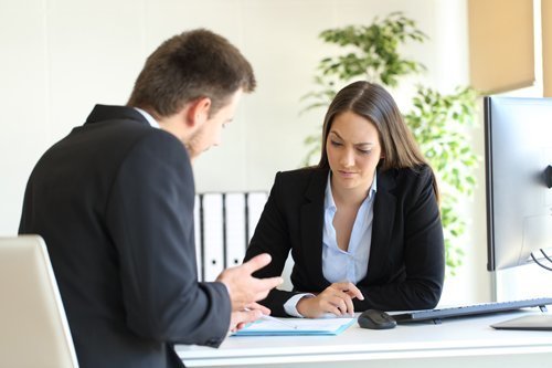 man and women in suit across table from each other negotiating