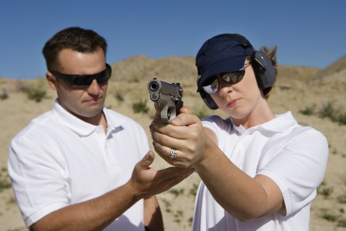 mujer apuntando con un arma como parte de un entrenamiento de armas de fuego