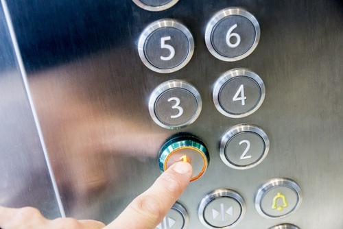 Person pressing an elevator button - elevator accident lawsuits can lead to money settlements for the victims
