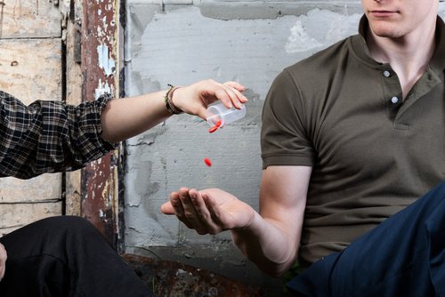 hombre dando pastillas a otra persona