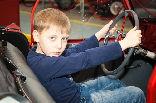 Un niño joven detrás del volante de un automóvil.