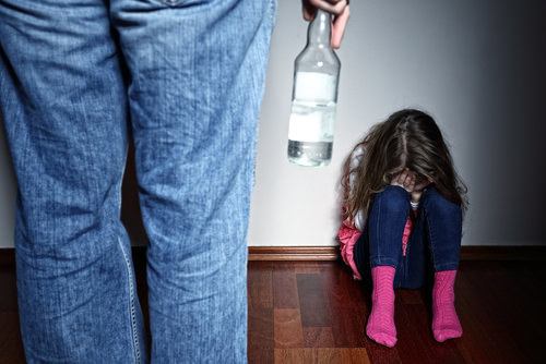adult in front of child holding bottle of alcohol