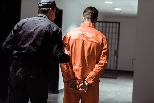 preso siendo llevado por un guardia a una celda de la cárcel - una condena por el Código Penal 417.6 PC puede llevar hasta 3 años en custodia