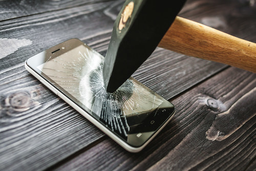un pico siendo usado para romper un teléfono celular