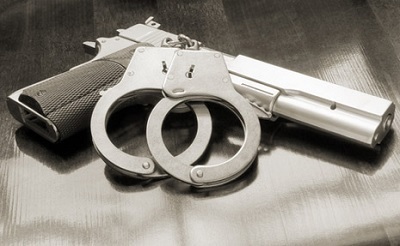 Gun and handcuffs against a grey background