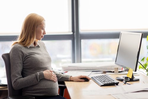 pregnant woman in office at desk with computer