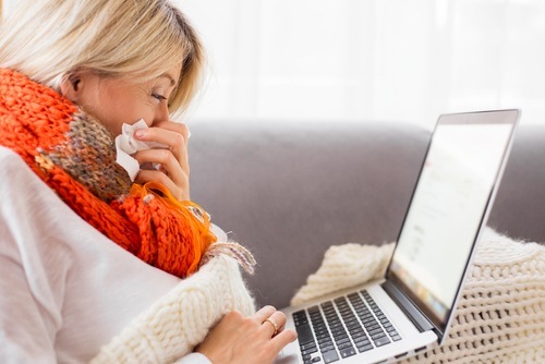 Woman with laptop sneezing