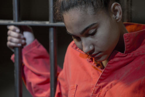 young female inmate inside of a jail cell - bringing contraband into a California jail or prison is a violation of Penal Code 4573.5 PC