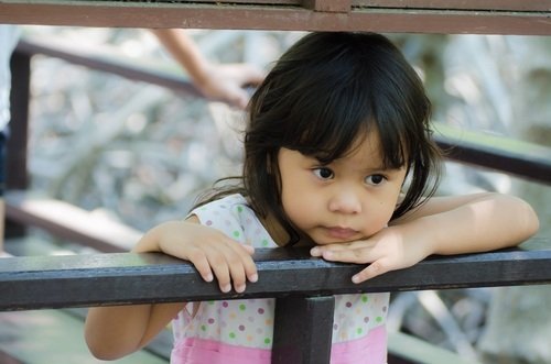 lonely little girl looking over a balcony