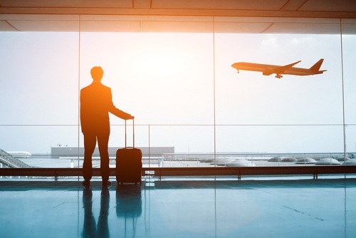 man in business suit lookout out airport window at airplane