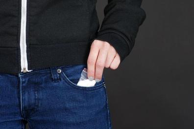 close-up of man putting baggie of white powder into his pocket