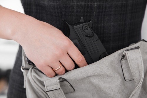 woman pulling out a gun from her purse as an example of aggravated assault in California 