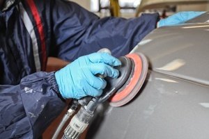 auto body worker sanding a newly painted car