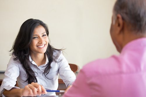 smiling female office manager interviewing an older male candidate