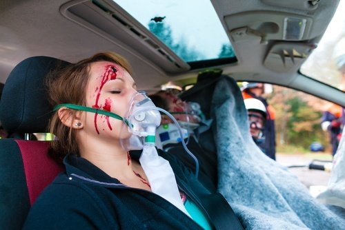 Girl with bloody face and oxygen mask inside emergency vehicle
