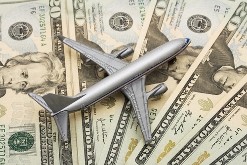 Model airplane sitting on stack of $20 bills