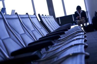 Row of empty airport seats with a solitary person seated in the distance looking down