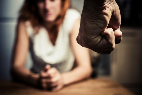 Close-up on man's clenched fist with scared woman in background