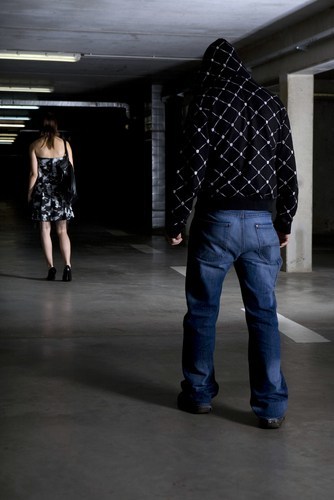 man stalking dressed-up woman in a parking garage
