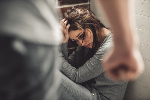 Man clenching fist as a battered woman