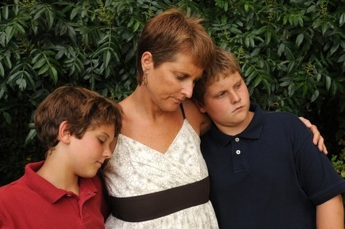 grieving woman with her two young sons - families of murder victims may be able to bring a wrongful death lawsuit in civil court