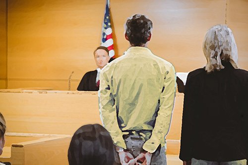 defendant with attorney standing before judge in a courtroom