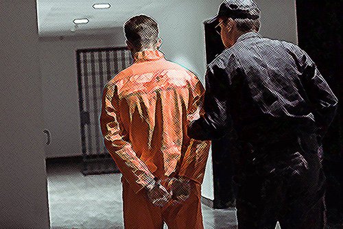 preso con mono naranja siendo llevado a una celda de la cárcel - una condena por el Código Penal 242 PC puede llevar hasta 6 meses en la cárcel