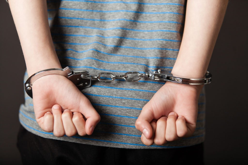 A child murder suspect in handcuffs being tried in adult court.