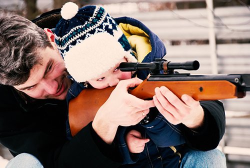 father teaching son how to look through scope