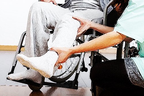 enfermera atendiendo la pierna de un paciente lesionado en una silla de ruedas