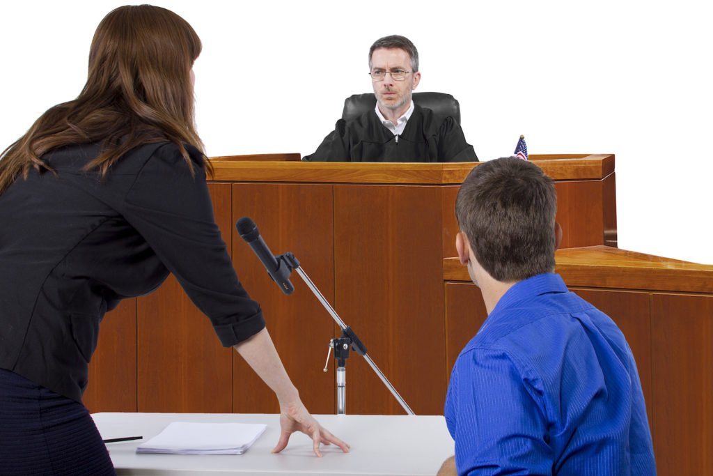 A criminal defense attorney with her client advocating on his behalf in front of a judge