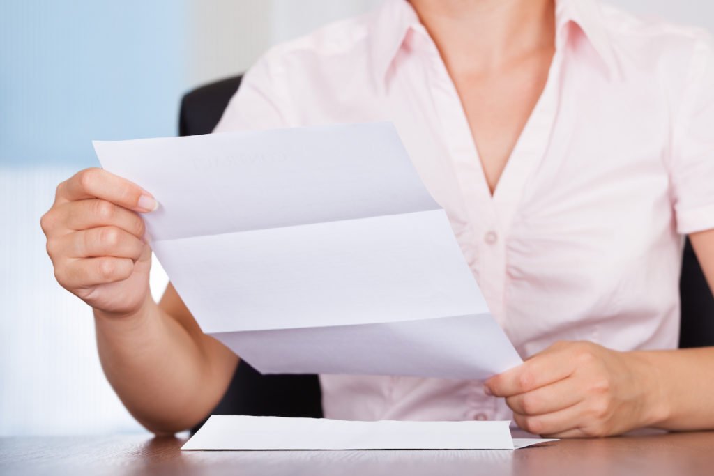 Mujer abriendo una carta enviada como parte de una estafa