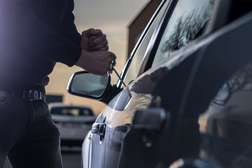 Man using a slim jim to break into a car as an example of grand larceny of a motor vehicle per Nevada NRS 205.228