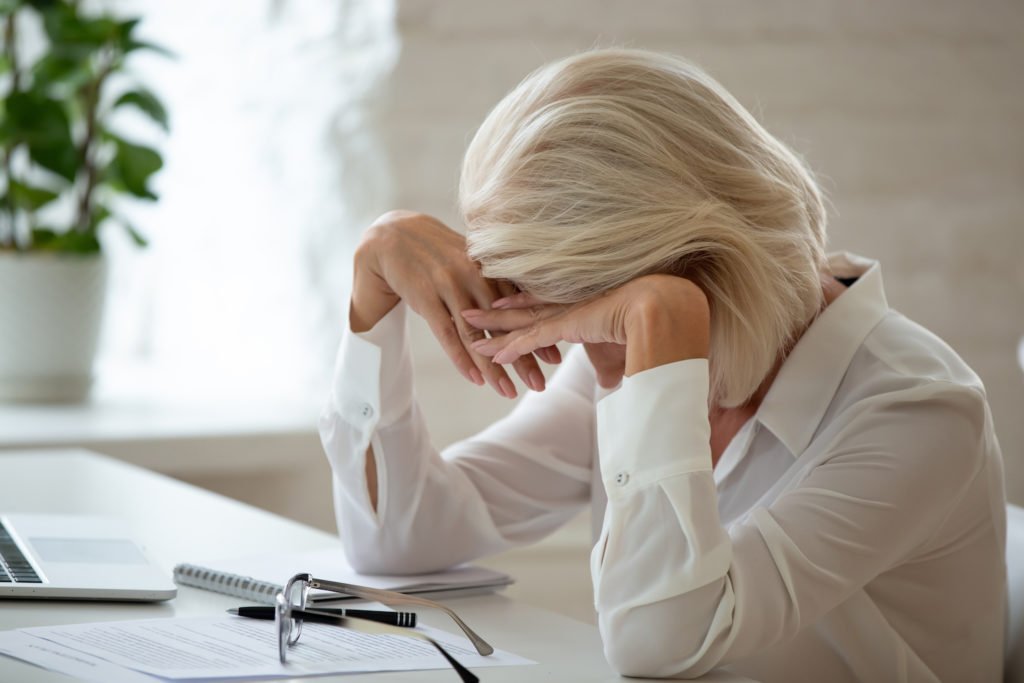 Mujer mayor en escritorio mirando angustiada